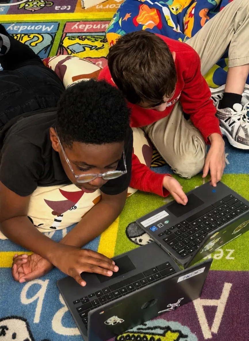Two elementary students working together on a roller coaster challenge in the Qweebi online makerspace.