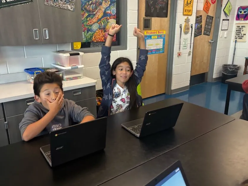 Elementary students reacting to a roller coaster challenge in the Qweebi online makerspace; one successful, one a little defeated.