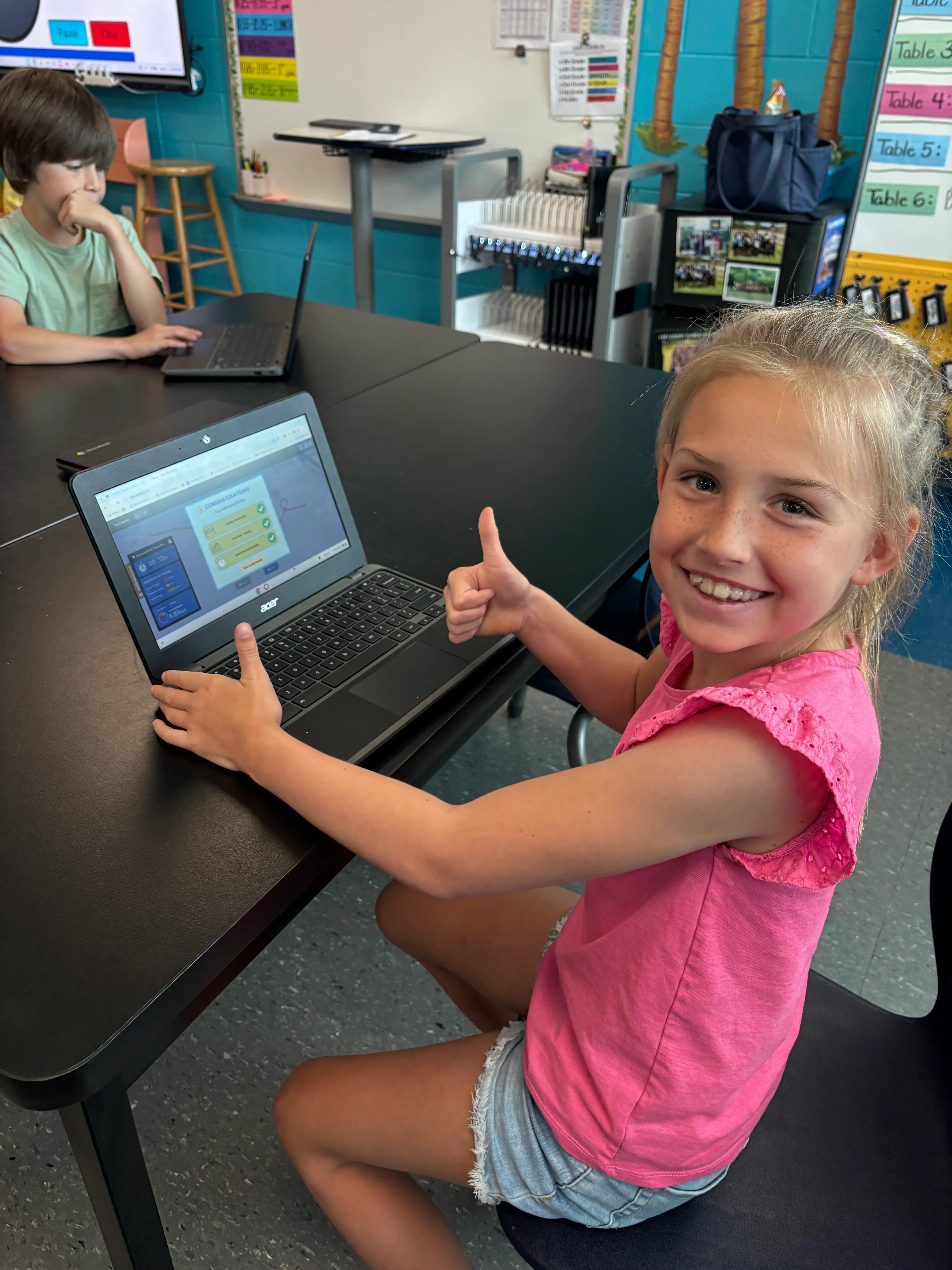 A young student celebrating completing a roller coaster challenge in the Qweebi online makerspace.