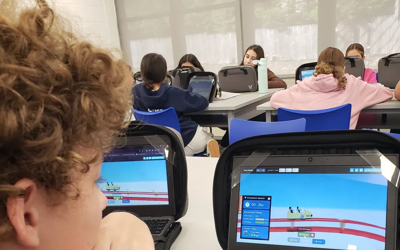 Students in a classroom testing their roller coaster designs on Chromebooks.