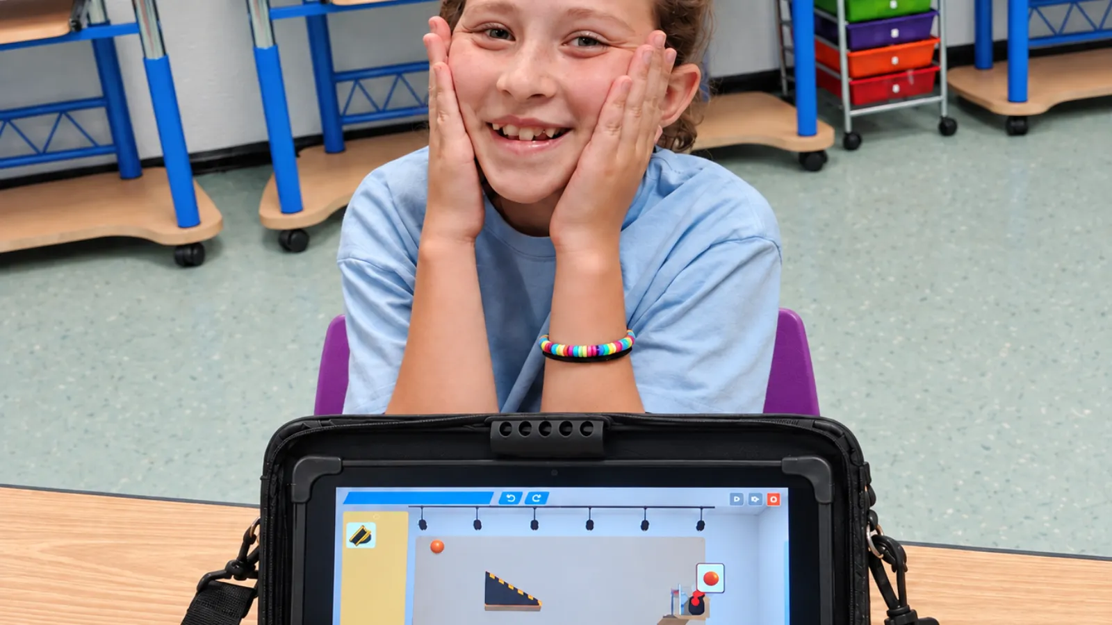 A student celebrating after finishing her Rube Goldberg build in Qweebi's online makerspace.