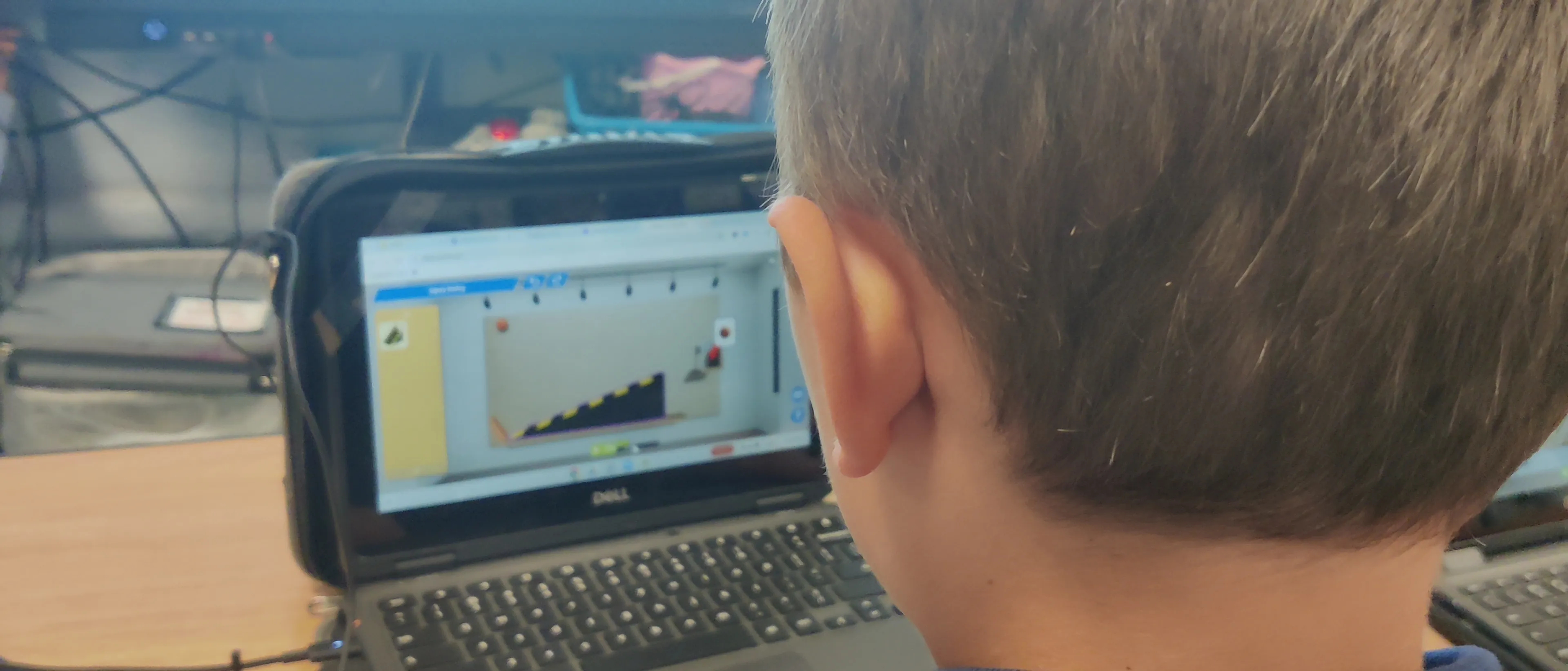 A student building a Rube Goldberg machine in Qweebi, testing a ramp-and-marble sequence.