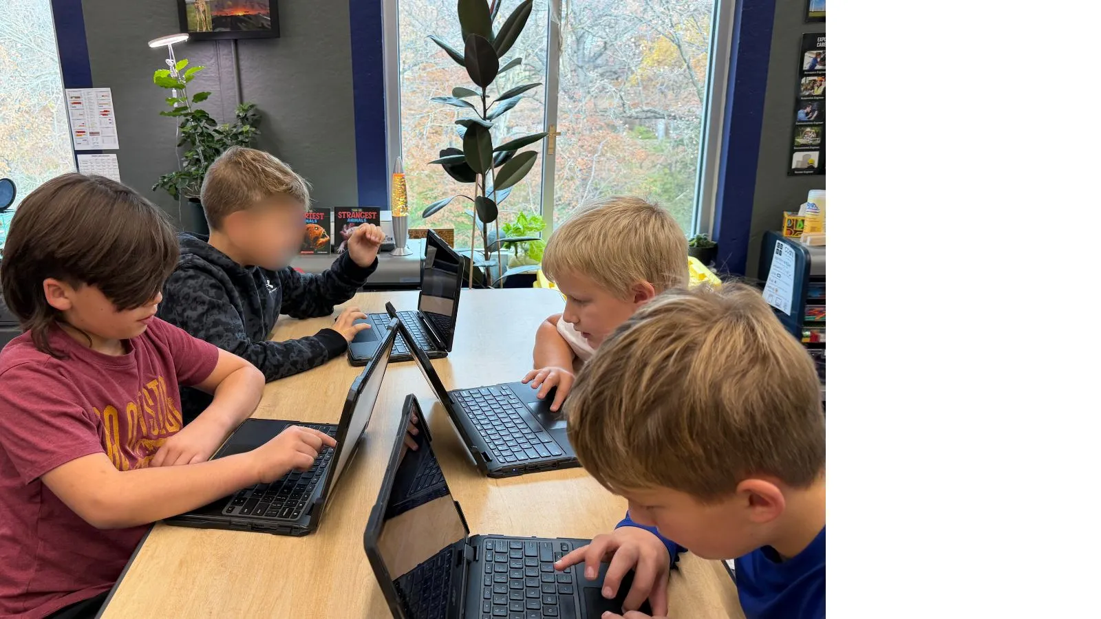 A table group of elementary students comparing their Rube Goldberg machine builds in Qweebi.