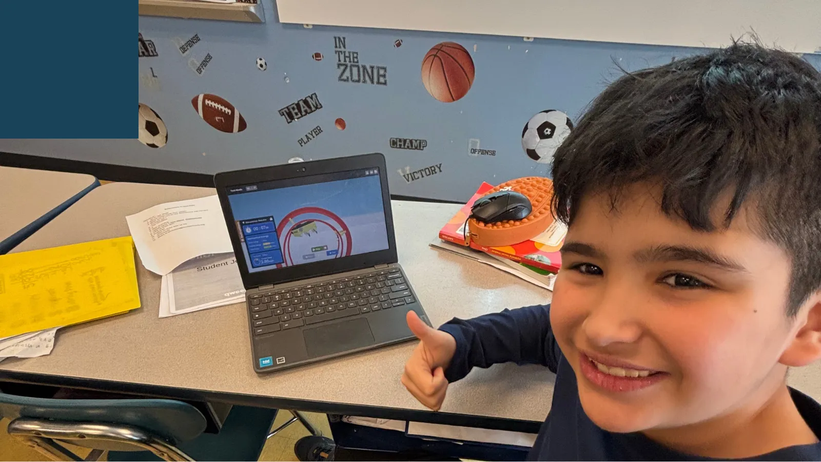 A fourth grader smiling while building his roller coaster in the Qweebi online makerspace.