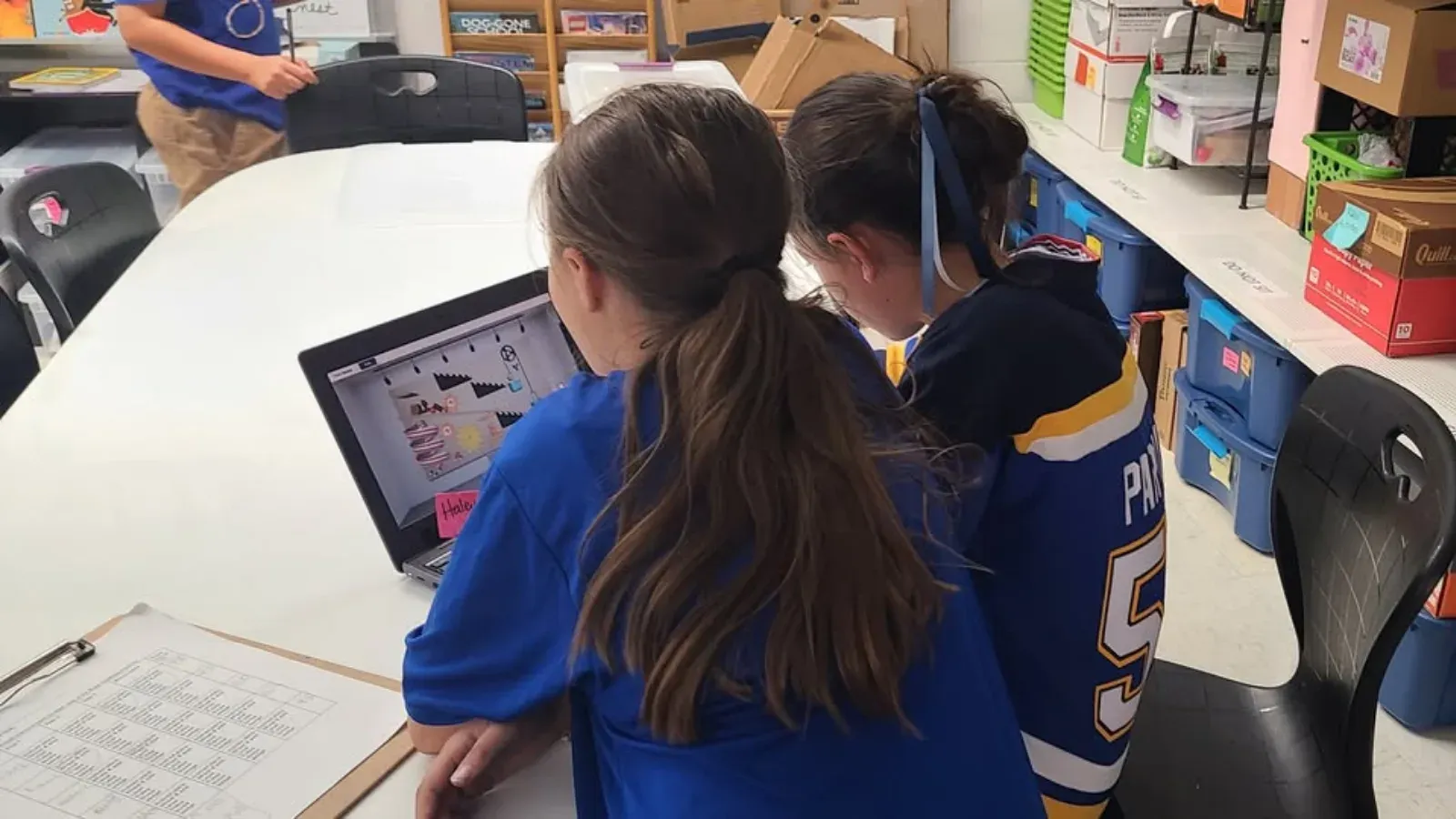 Two students sharing a laptop to work on a Qweebi project together.